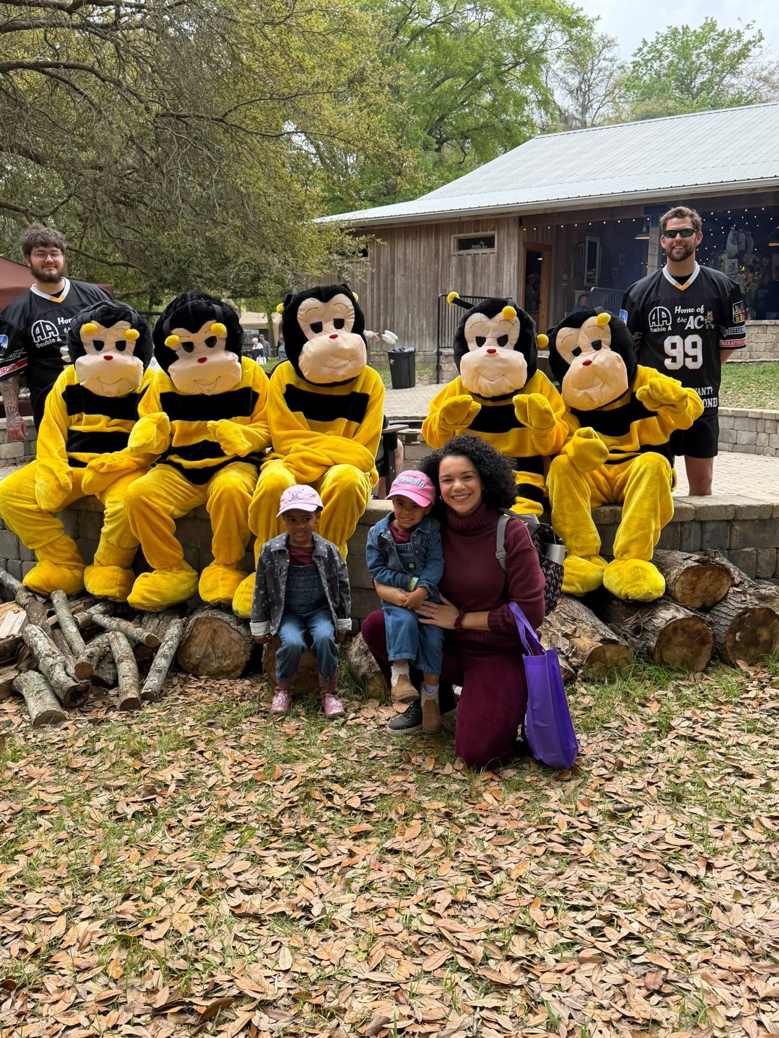 Mom and two daughters posing with AC Bee mascots at an outdoor event
