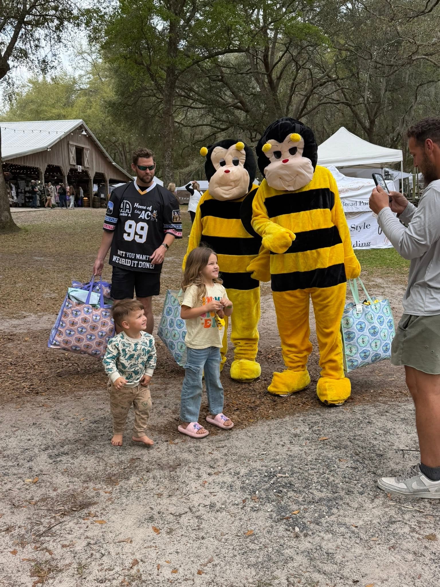 Two young children posing with AC Bee mascots and Double A team at a fair